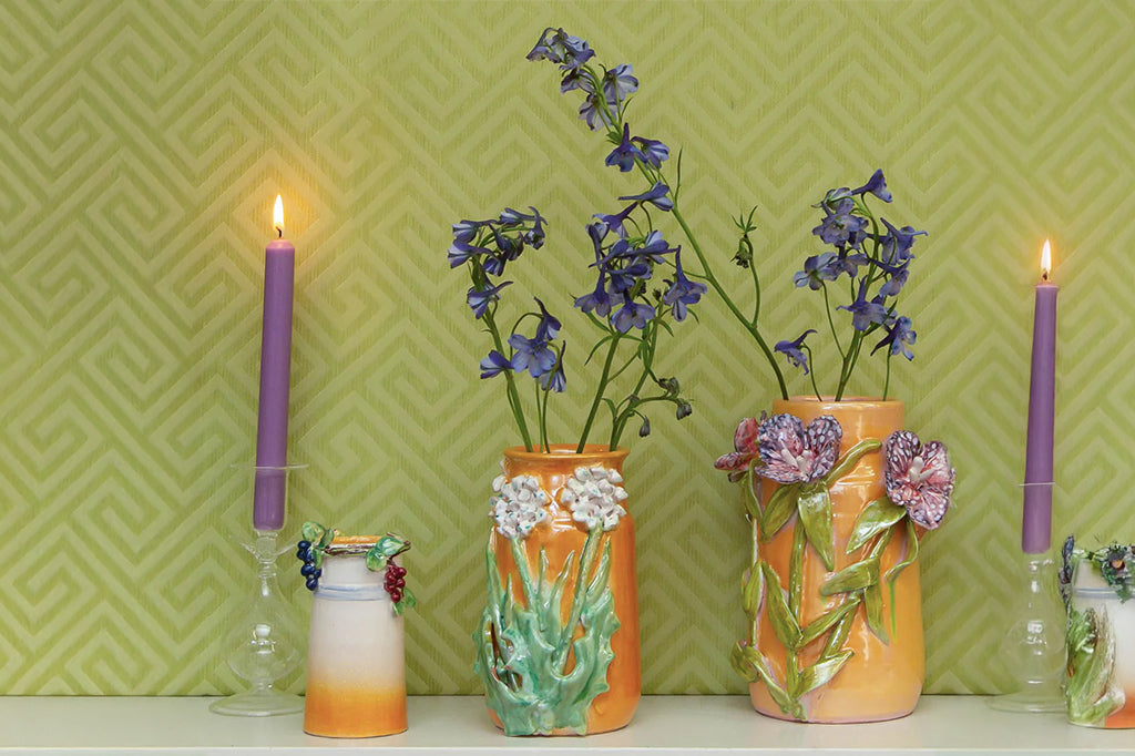 3-d flowers on mango colored vase with live florals inside set on counter staged with taper candles 