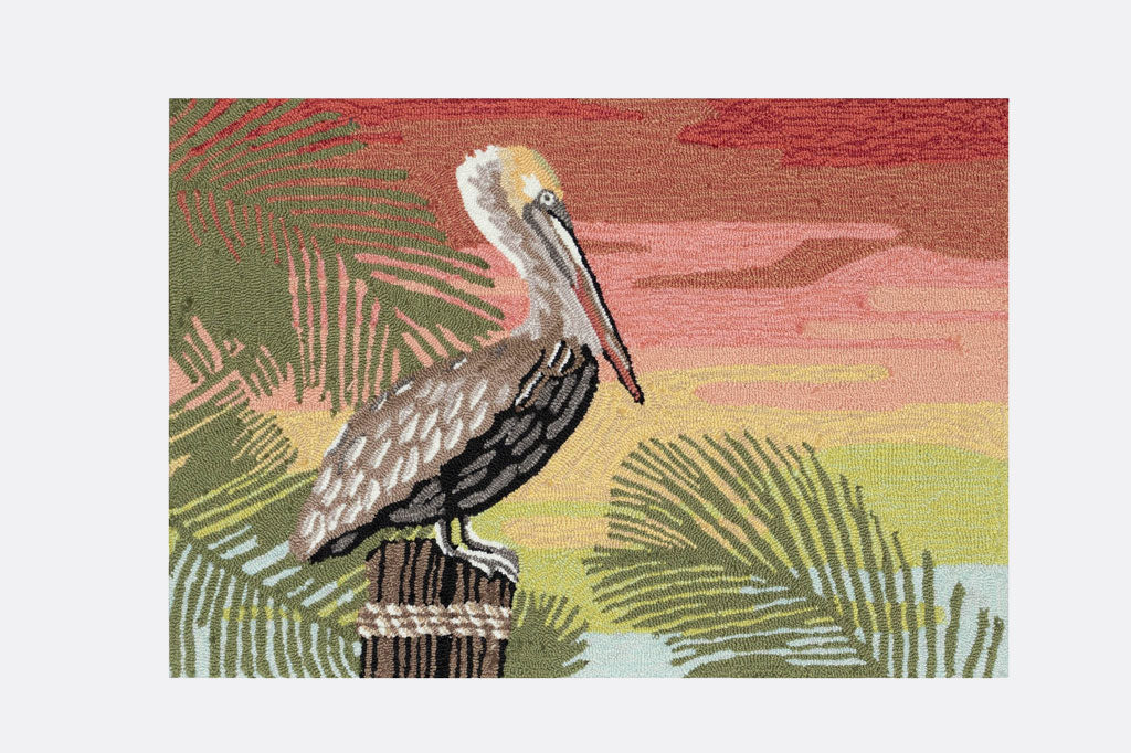 Indoor/Outdoor rug with pelican perched on a wooden post surrounded by tropical green leaves on a bright orange and pink sunset background