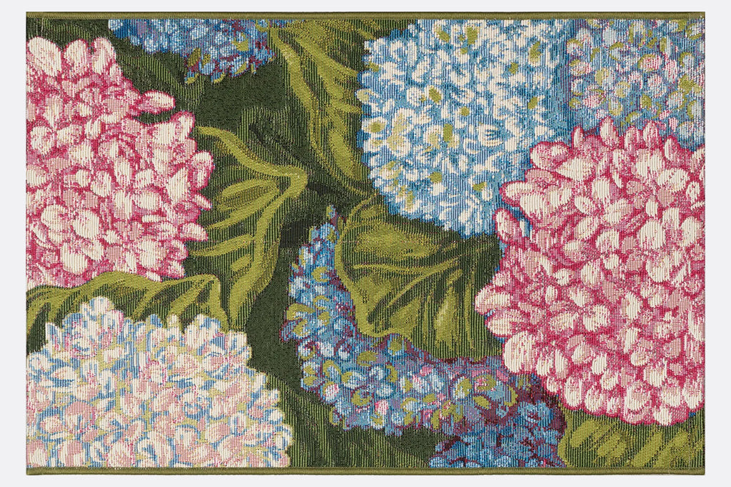 A rug with floral patterns featuring blue, pink, and white hydrangeas and green leaves.