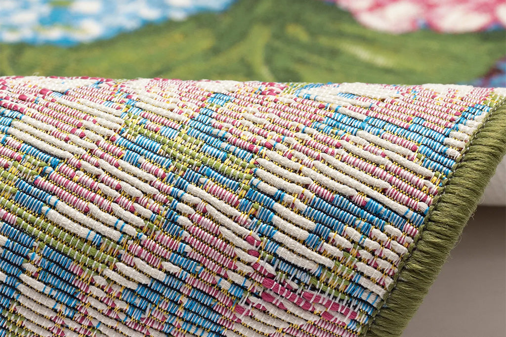 A rug with floral patterns featuring blue, pink, and white hydrangeas and green leaves.