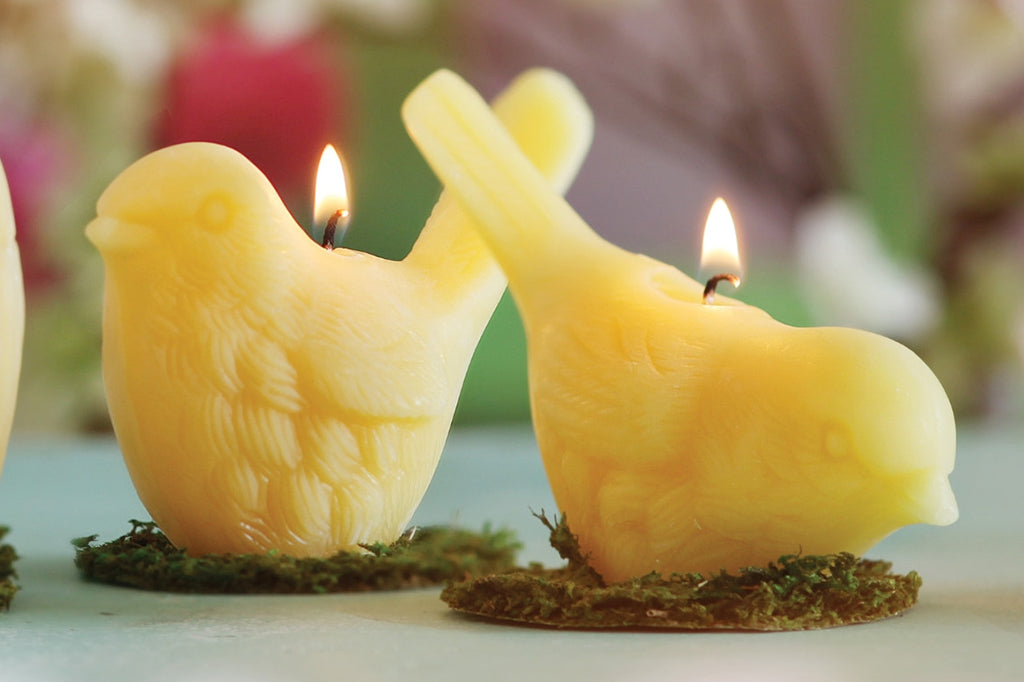 Pair of beeswax bird candles lit and placed on table 