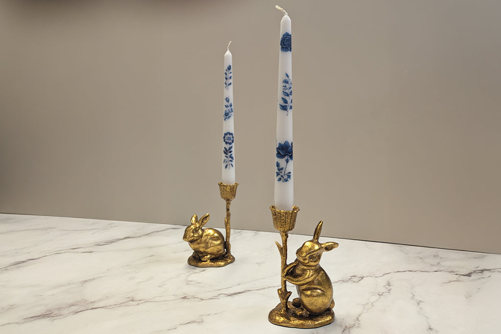 blue and white printed taper candles held in golden bunny taper candle holder 