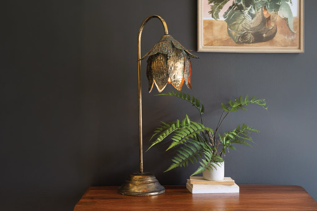 metal tulip curved tulip lamp with blue patina set on desk next to fern plant 
