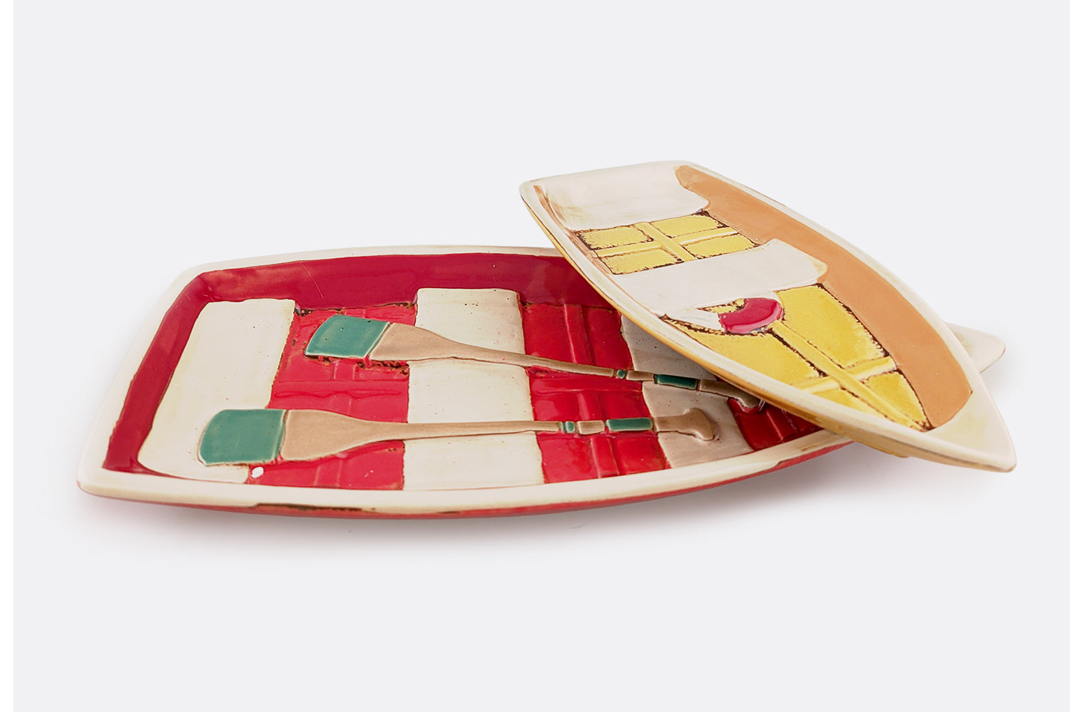 Decorative ceramic dishes shaped like row boats with sculpted embellishments like paddles or bench seating