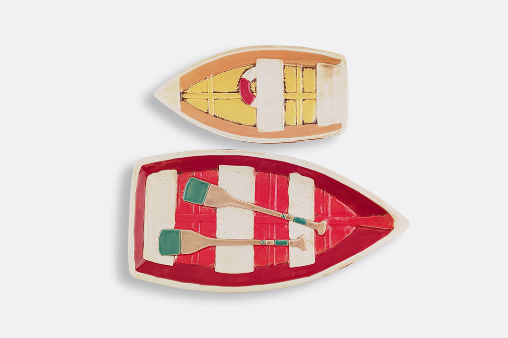 Two ceramic boat-shaped plates with decorative elements on a light gray background
