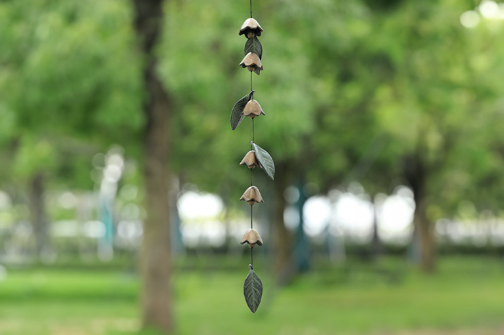 Buttercup Chain Windchime shown outside amidst trees