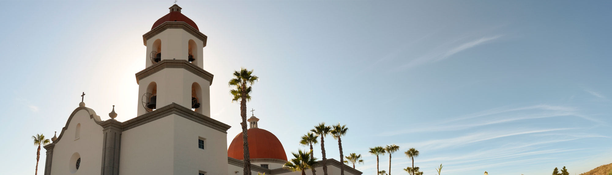 panorama view of Mission San Juan Capistrano backlit by the sun