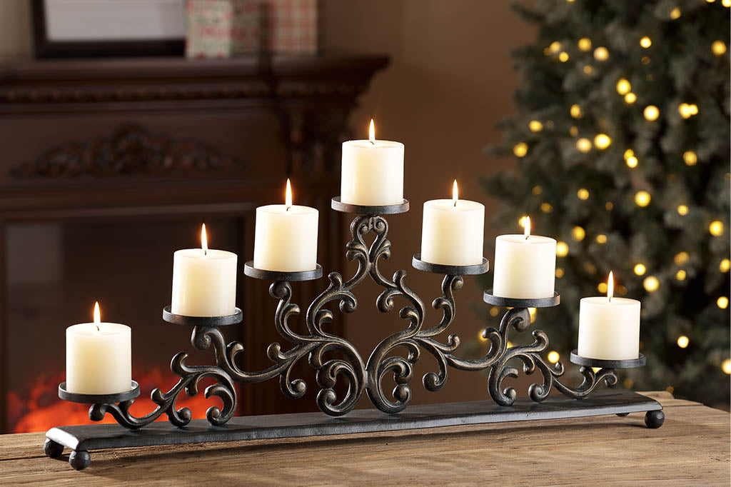 Cast metal candelabra holding 7 pillar candles is comprised of Filagree scrollwork in an elegant triangle, displayed on dining table in a room decorated for Christmas