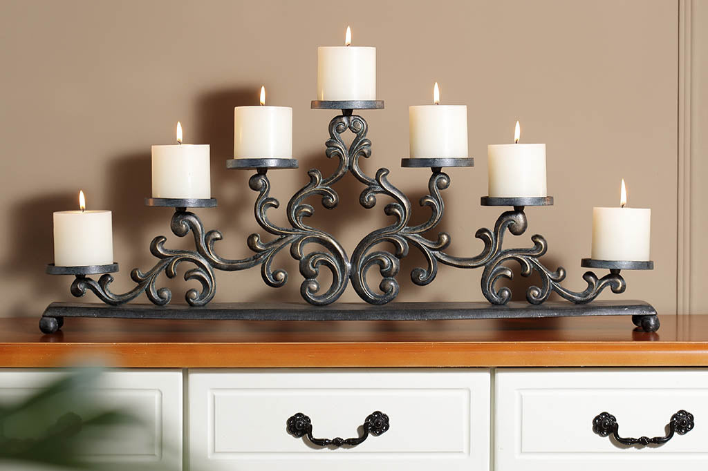 Cast metal candelabra holding 7 pillar candles is comprised of Filagree scrollwork in an elegant triangle, displayed on bureau 