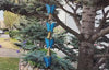 Blue Butterfly Wind Bells moving in the wind, hanging from spruce tree