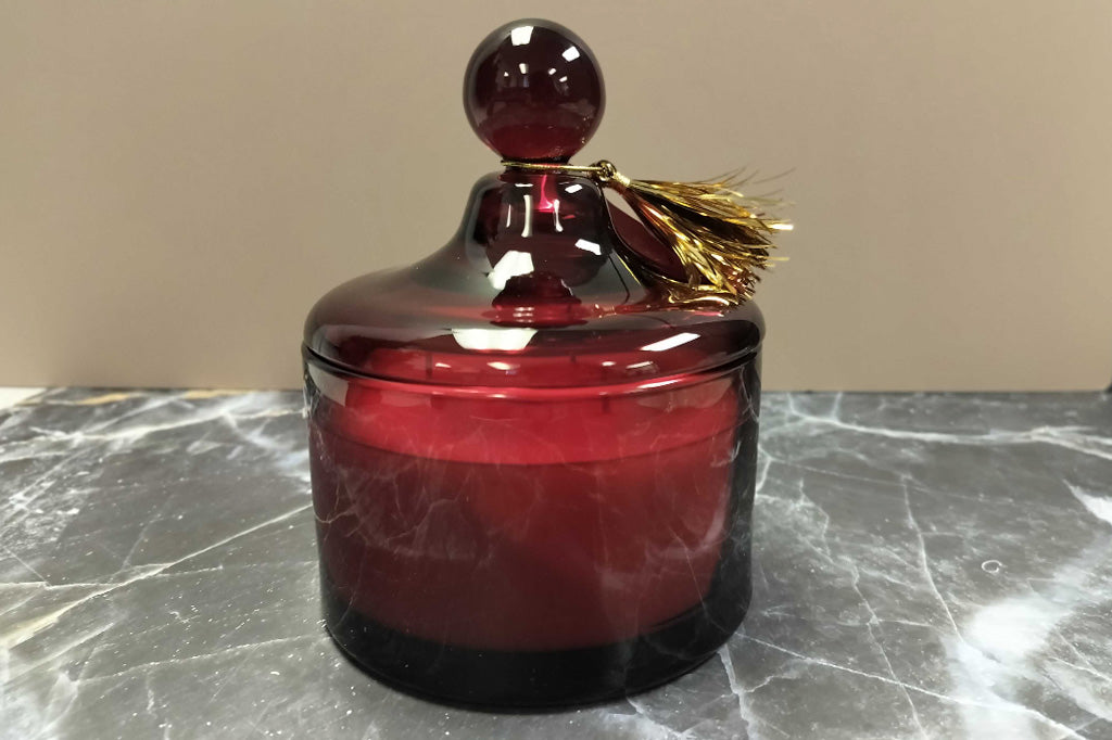 Red glass lidded candle shown with gold tassle tag