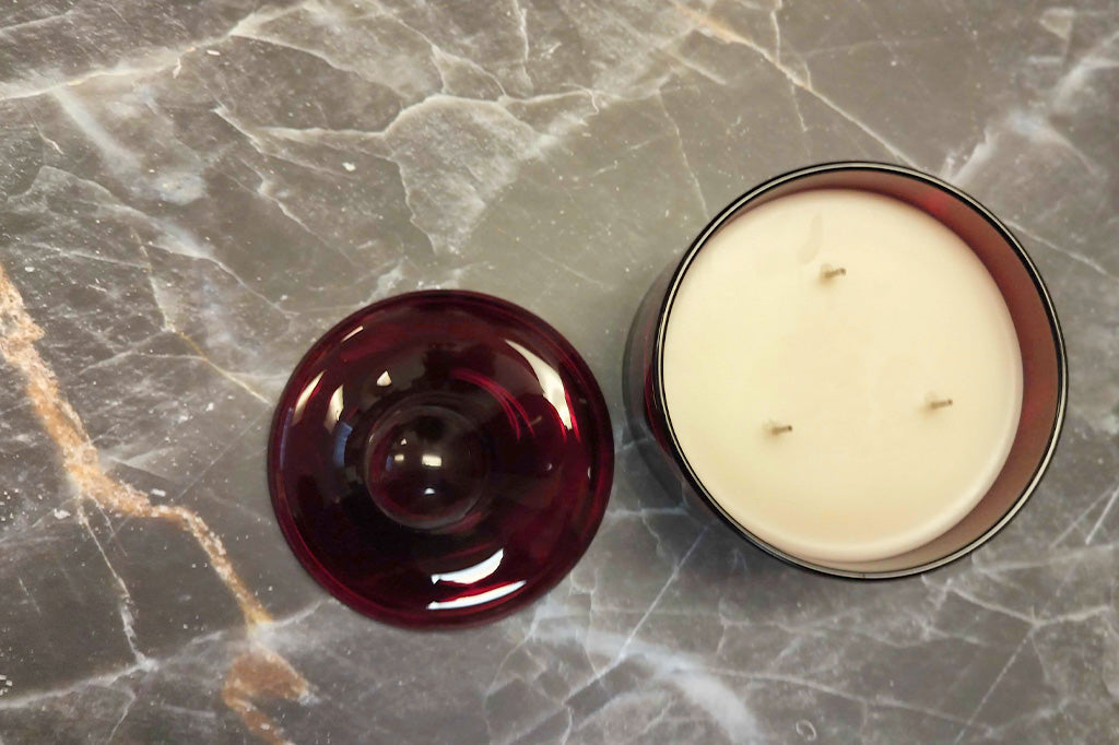 Red glass lidded candle shown on marble table