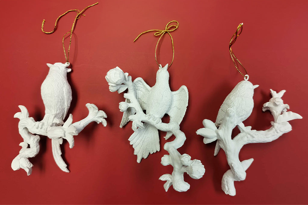 3 white bird ornaments with gold thread shown on red background