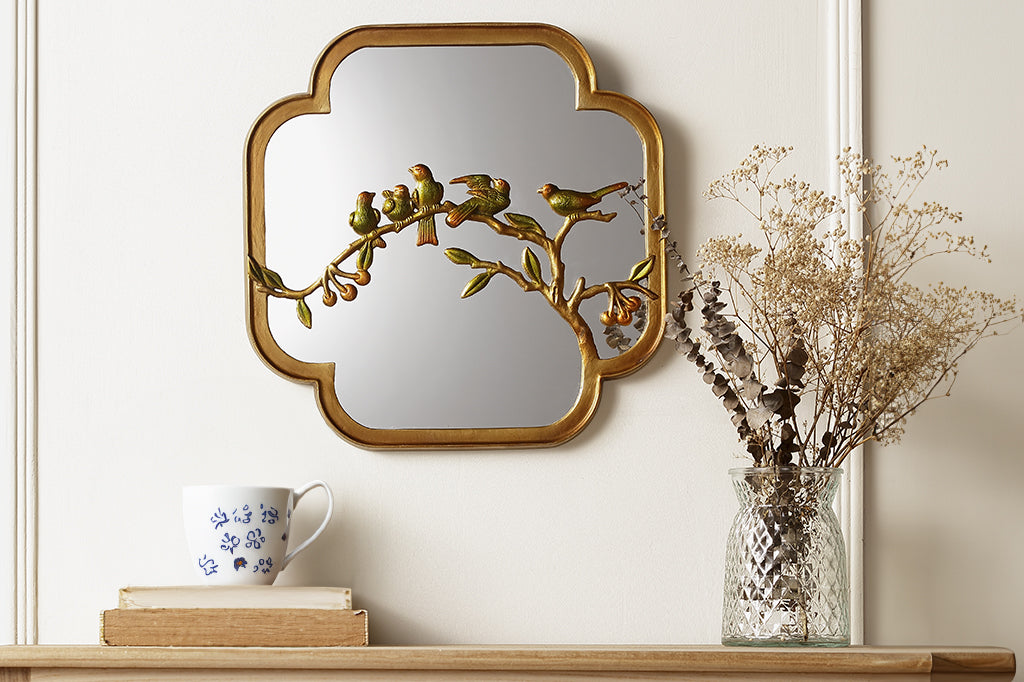 Chinoiserie mirror with golden and green birds on a branch feautured over a dresser
