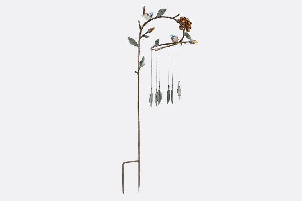 back view of cast metal bluebirds seated on whimsical branch of leaves and flowers. Staked windchime