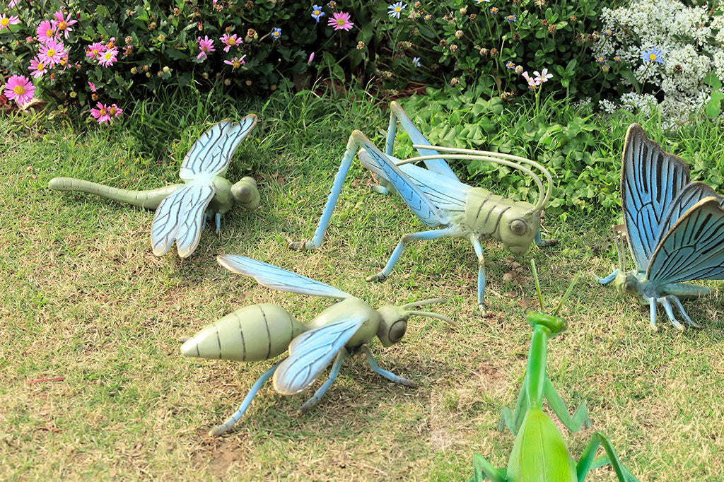top view of the blue and green finish on a cast metal dragonfly garden sculpture shown on grass with the coordinating insect sculpture collection