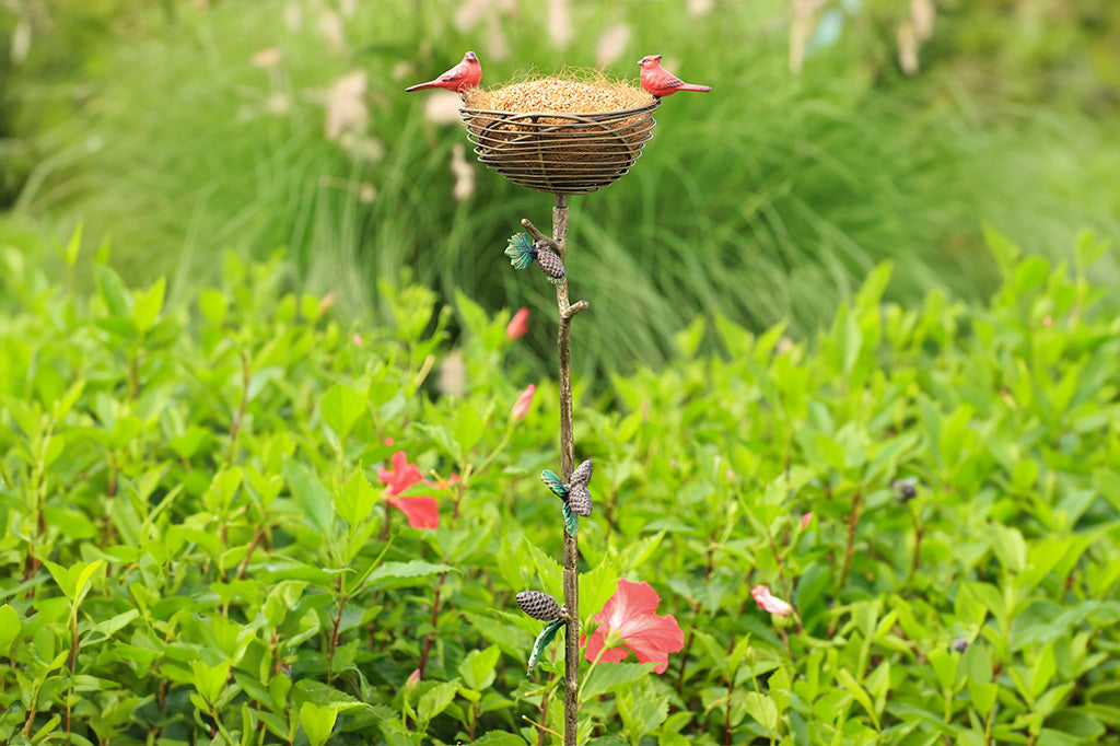 staked planter with red cardinals and a pine branch and pinecone motif adorns a bird nest used as a birdfeeder