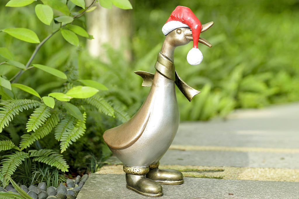 Decorative goose garden statue wearing a Santa hat in a garden setting