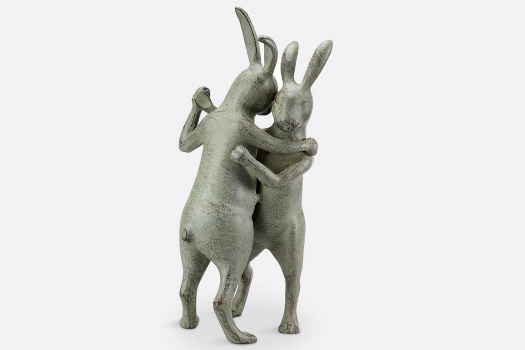 Garden sculpture of two rabbits with tall ears standing up and dancing together