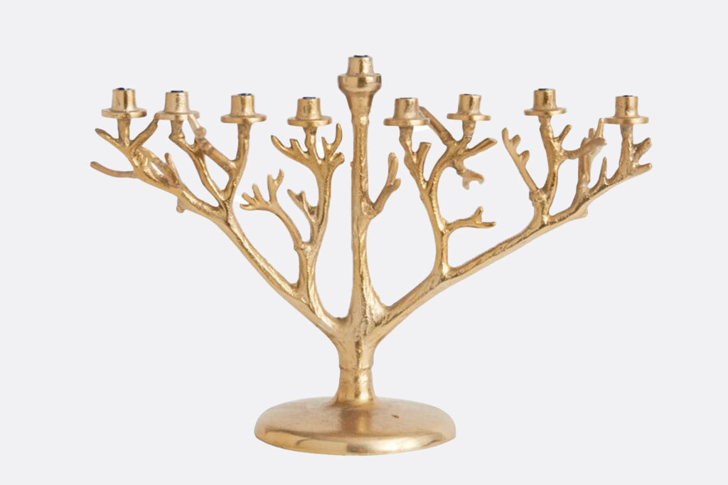 metal menorah in gold color with branch detailing on the body of candelabra 