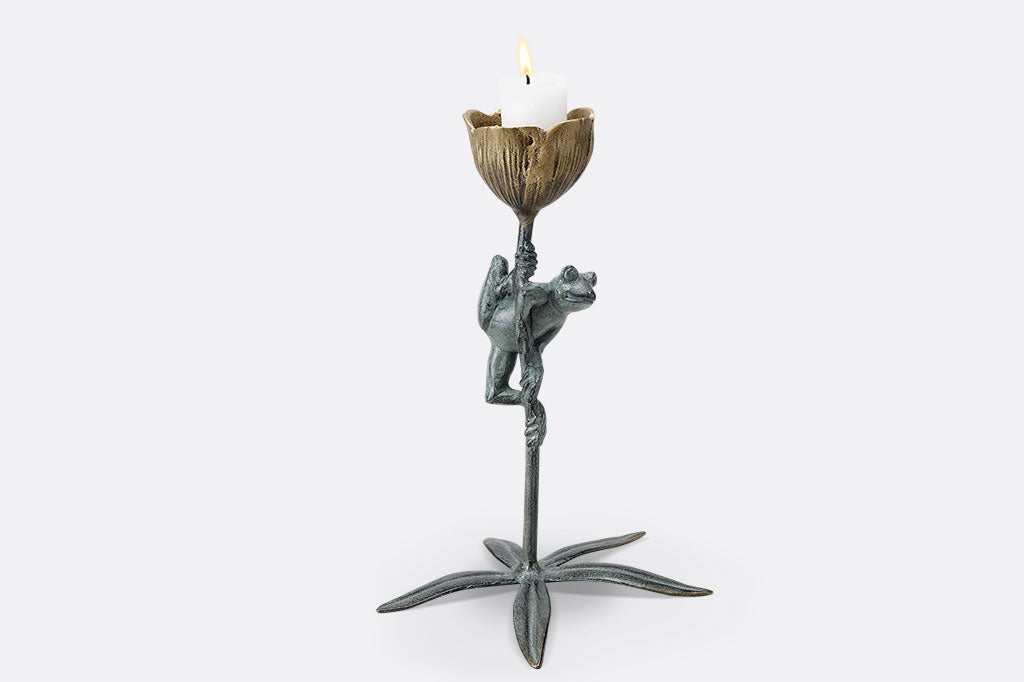 curious frog clings to a flower stem in a votive candle holder cast metal sculpture