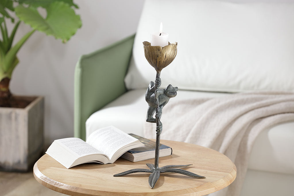 curious frog clings to a flower stem in a votive candle holder cast metal sculpture
