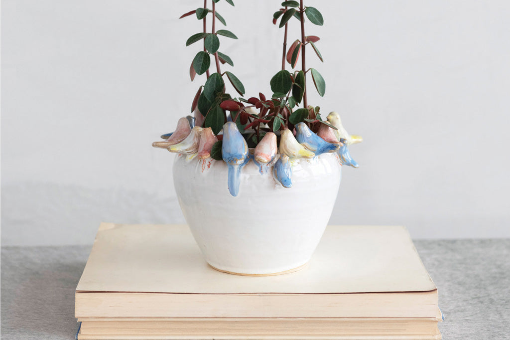 Flock together planter with ceramic birds around rim; holding leafy plant