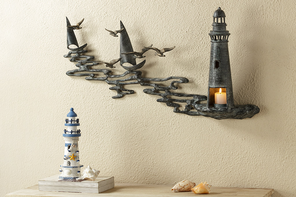 Wall art Votive holder cast metal sculpture of Lighthouse by the sea with 2 sail boats on the wall above a bedroom dresser
