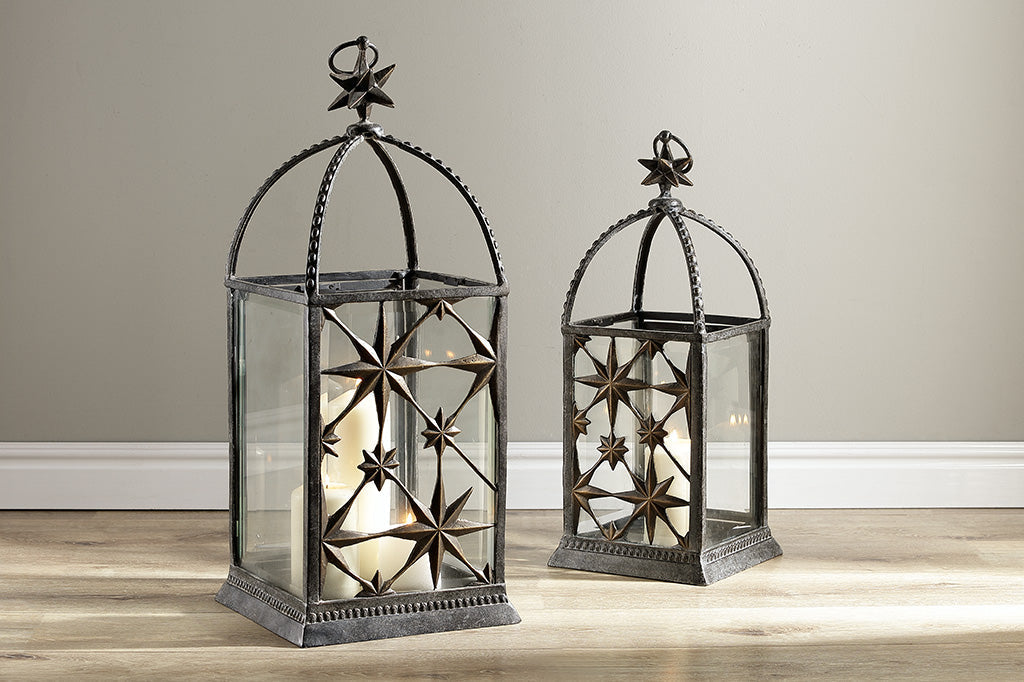 two starry night lanterns sitting on a wood floor
