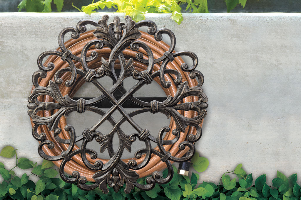 Fontaine hoseholder with scrollwork accents has a hose coiled around it andmounted to a wall