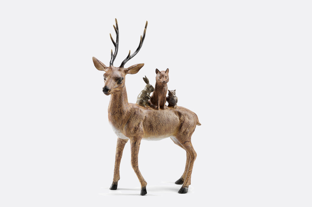 A sculpture of a bunny, fox, & owl cozy up together on a friendly deer
