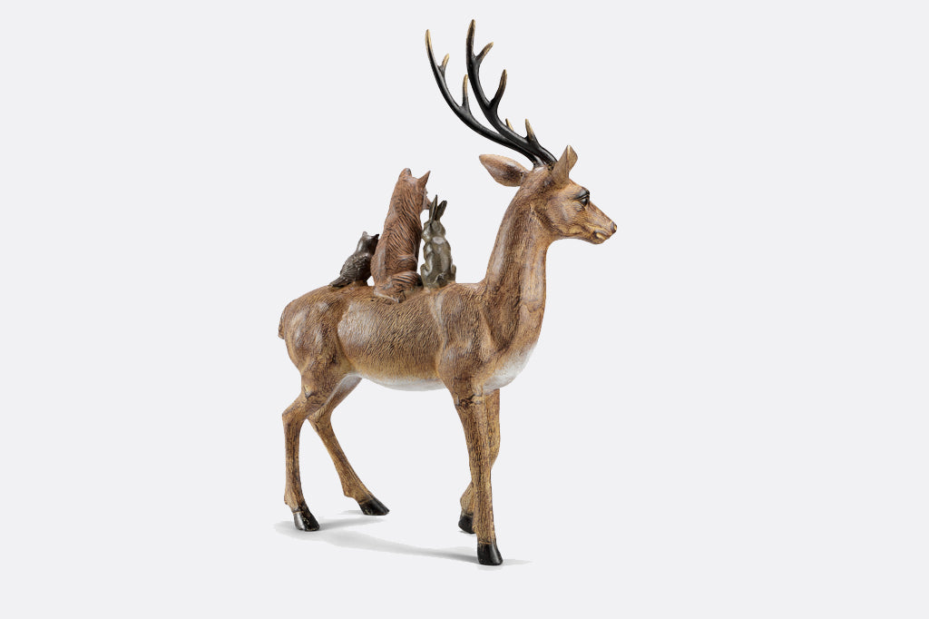Back view of a sculpture of a bunny, fox, & owl cozy up together on a friendly deer
