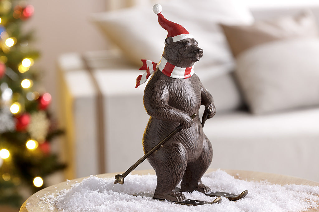 A bear wearing a santa hat and striped scarf is skiing as part of a holiday table display