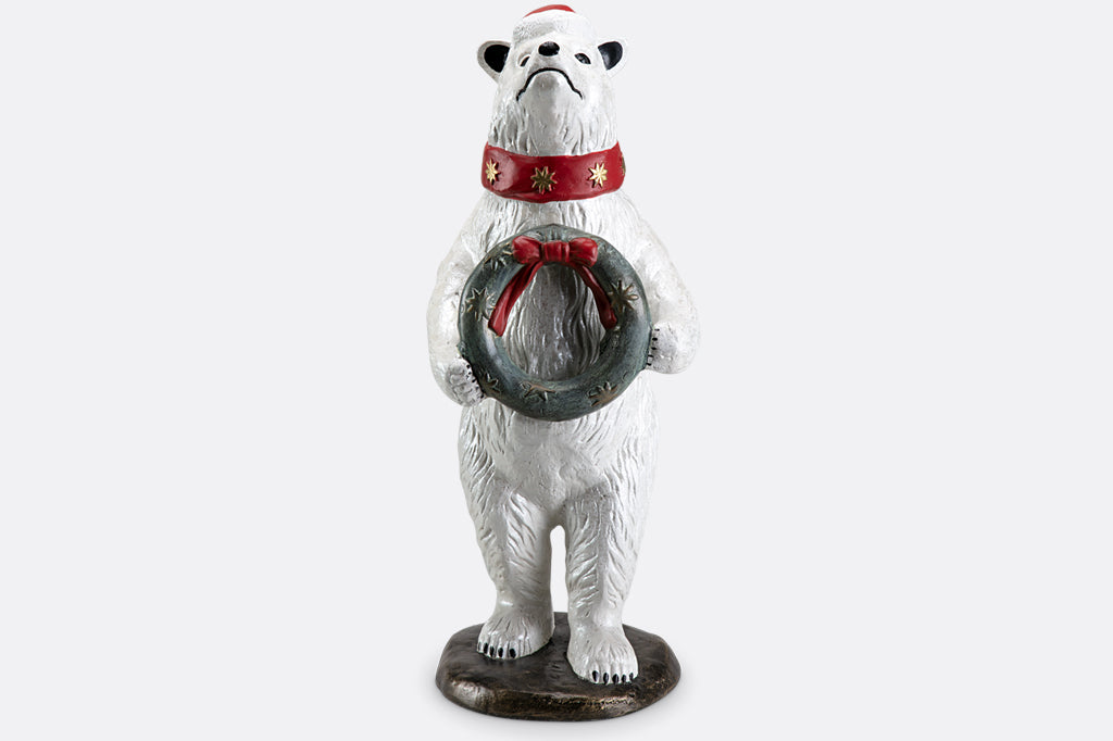 Polar bear wearing had and scarf  holding wreath sculpture