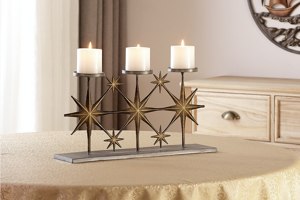 metal candleholder with large star motifs holding three candles placed on table