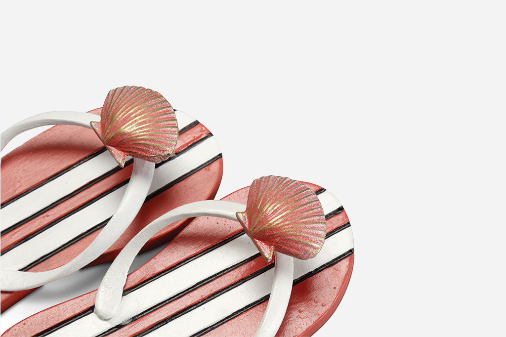 closeup of the scallop shell on a pair of wall hooks shaped like flip flops