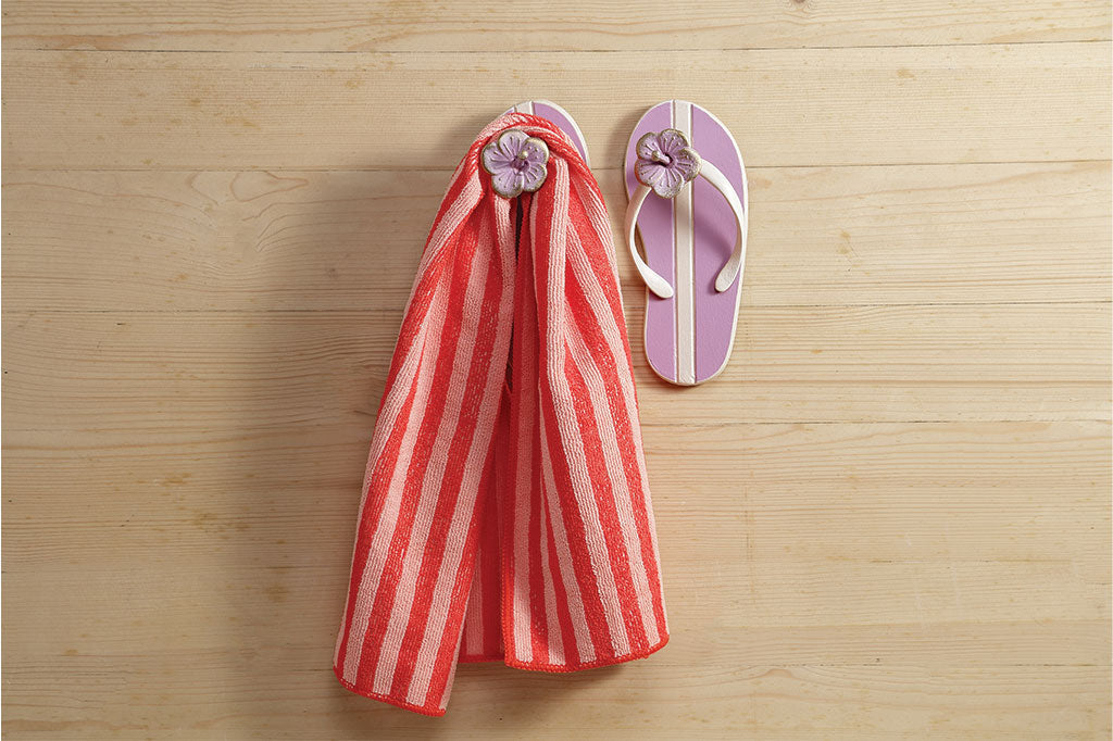 Pink flip flip wall hook with red stripped towel handing down 