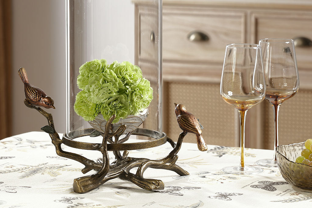 hurricane glass candleholder shown on dining table with 2 wine glasses and a floral bouquet inside