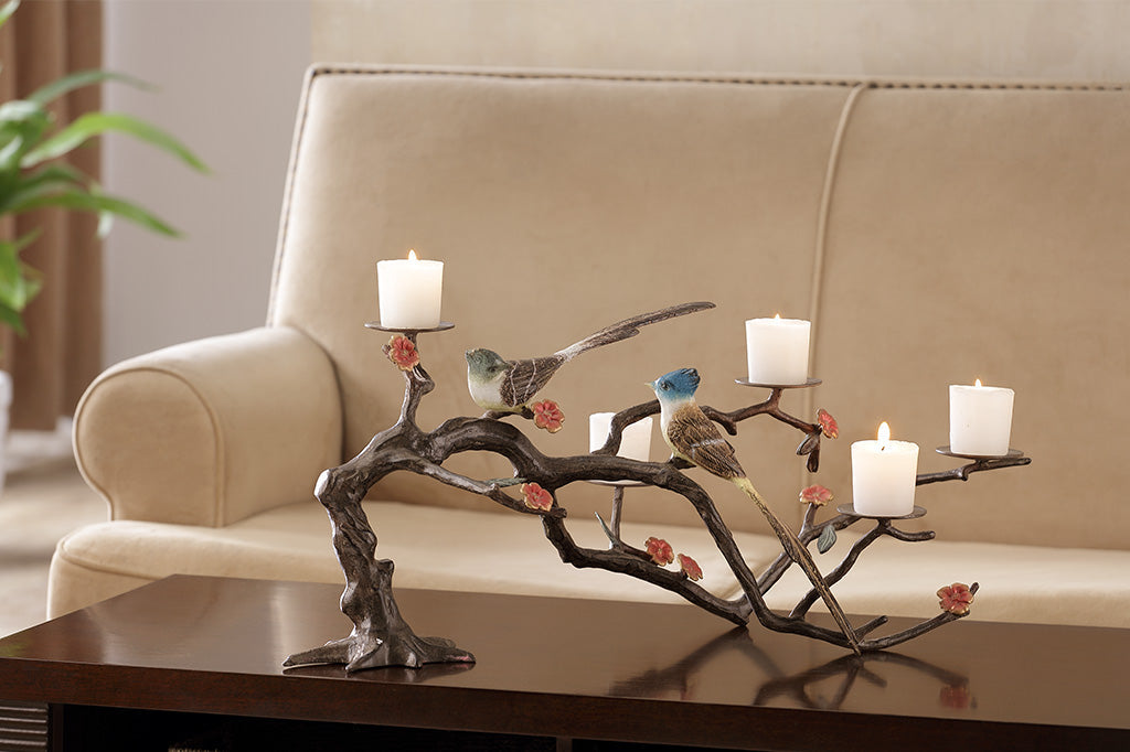 metal candelabra with branch and blossoms featuring two playful birds, holds up to 5 votive candles set on coffee table 