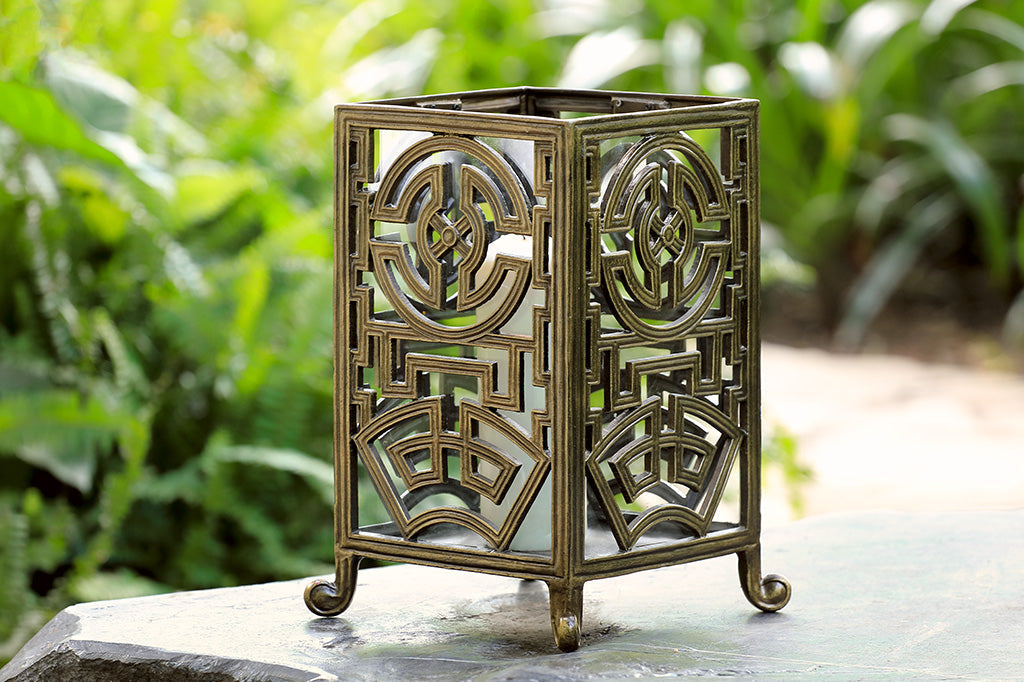 rectangle lantern with Asian inspired designs in a gold metal finish with white pillar candle inside 
