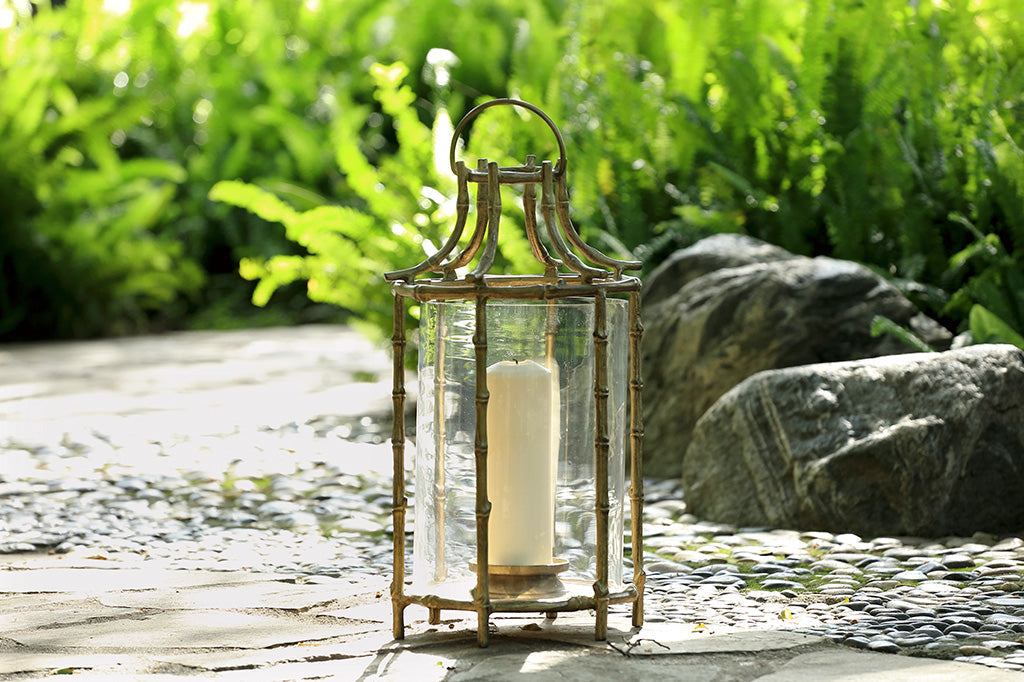 Outdoor metal lantern with bamboo details staged on rocks 
