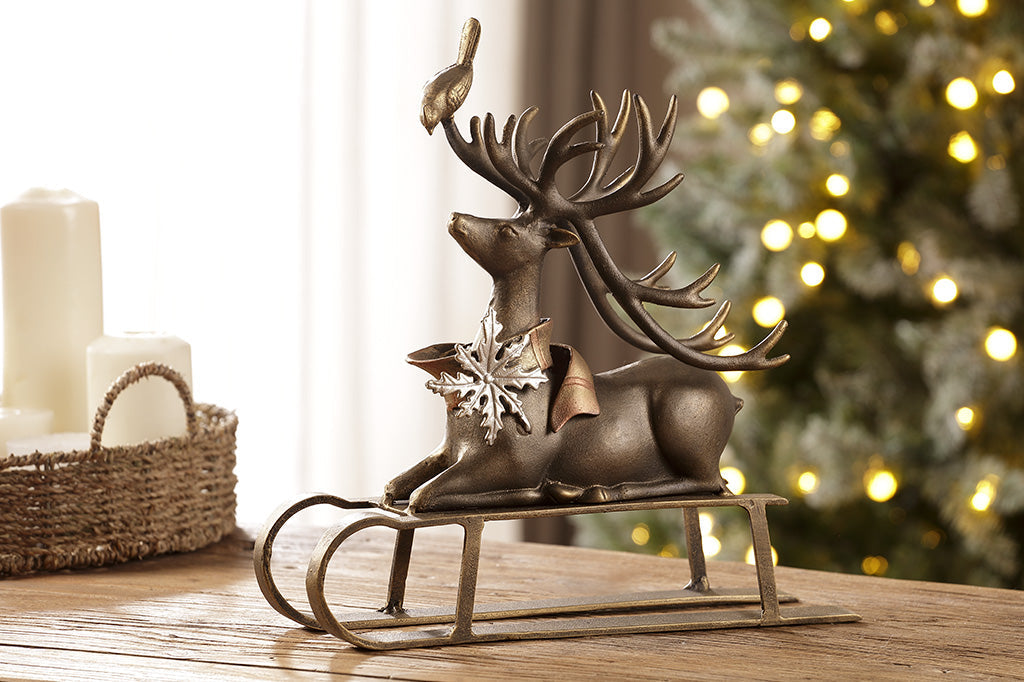 Cast aluminum reindeer sculpture with little bird friend on antlers seated on a sled 