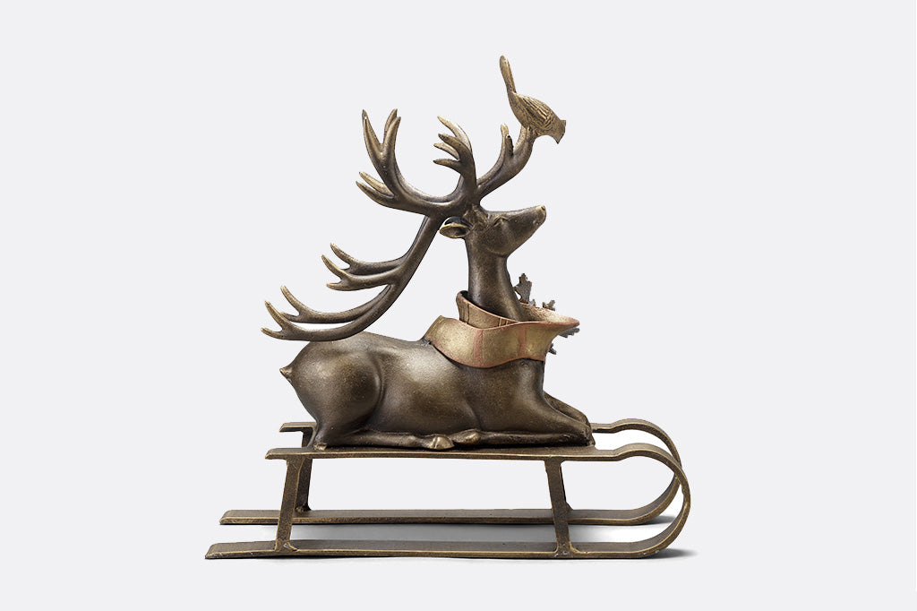 Cast aluminum reindeer sculpture with little bird friend on antlers seated on a sled right side profile 