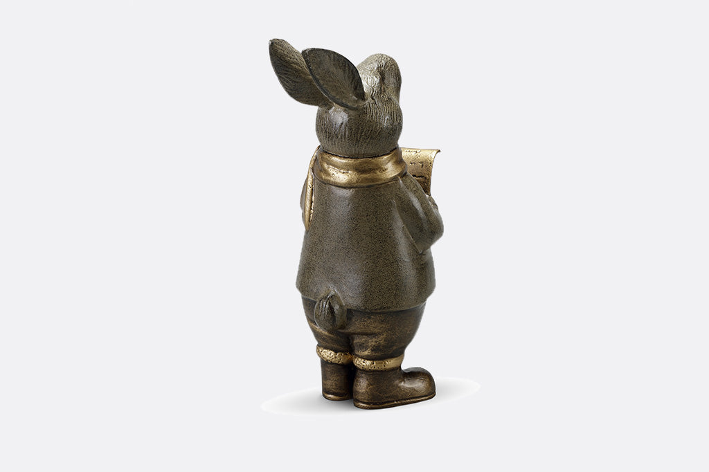 Caroling bunny sculpture holding a music sheer and wearing a hold scarf back view