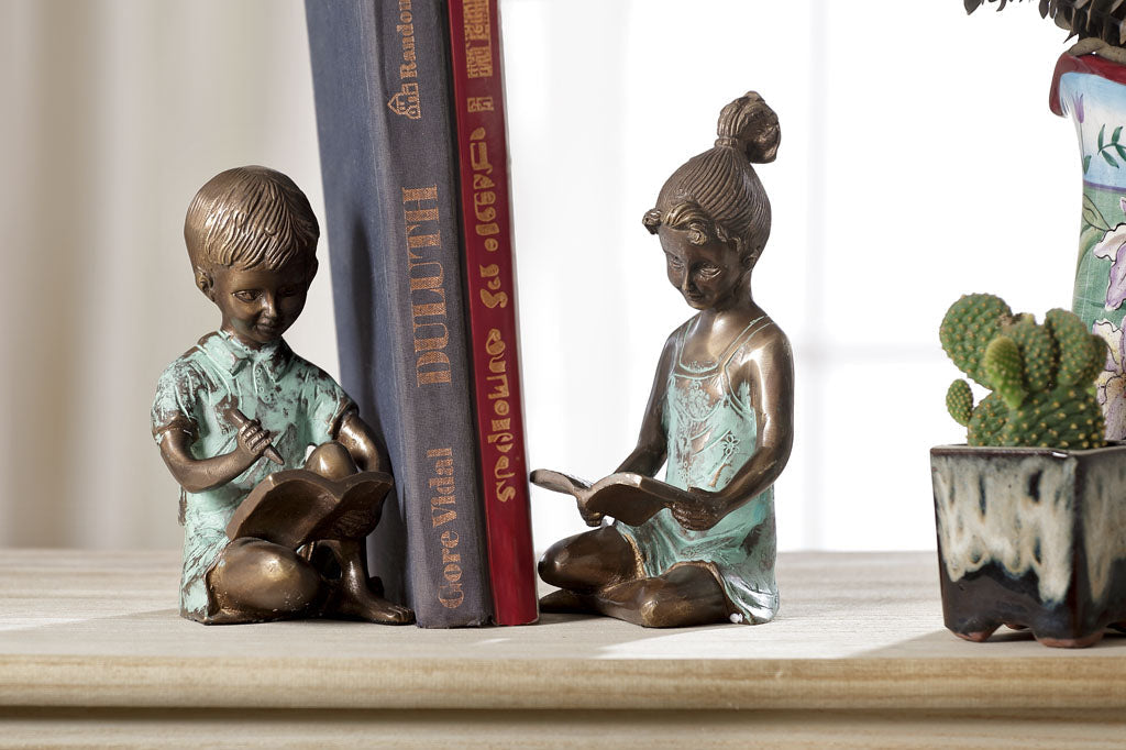 Brass bookends of a girl reading a book and a boy writing in a notebook