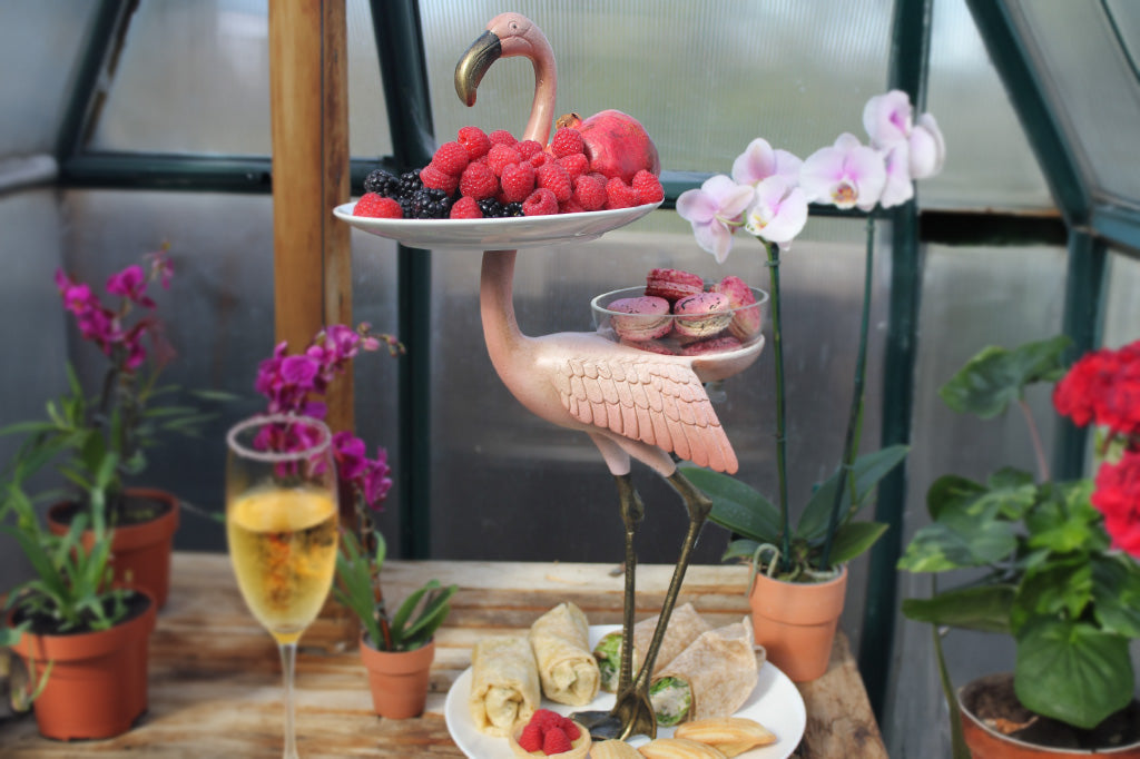 Flamingo serving bowl and plate stand amongst flowers and party food