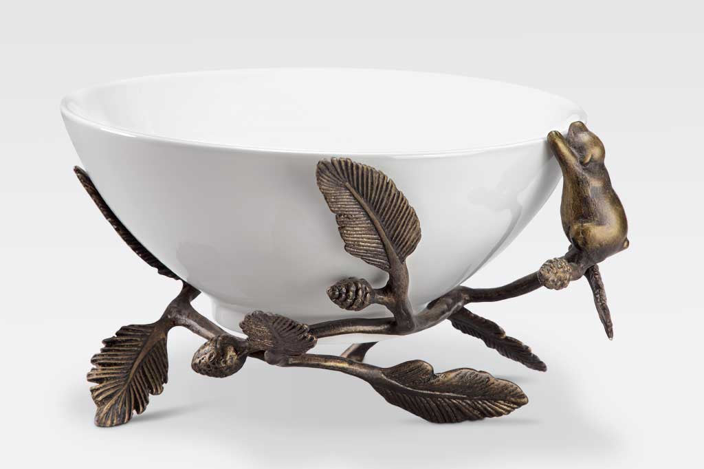 White ceramic serving bowl is supported by a bear climbing on decorative pine branches