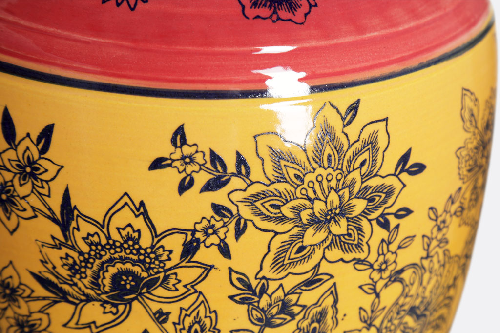 close up of floral stamped motif on yellow and rose glazed ceramic pot