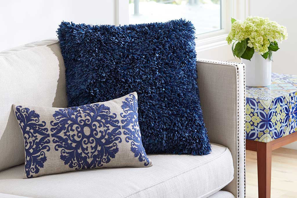 pillow with raised damask blue motif, lumbar shaped shown on beige couch