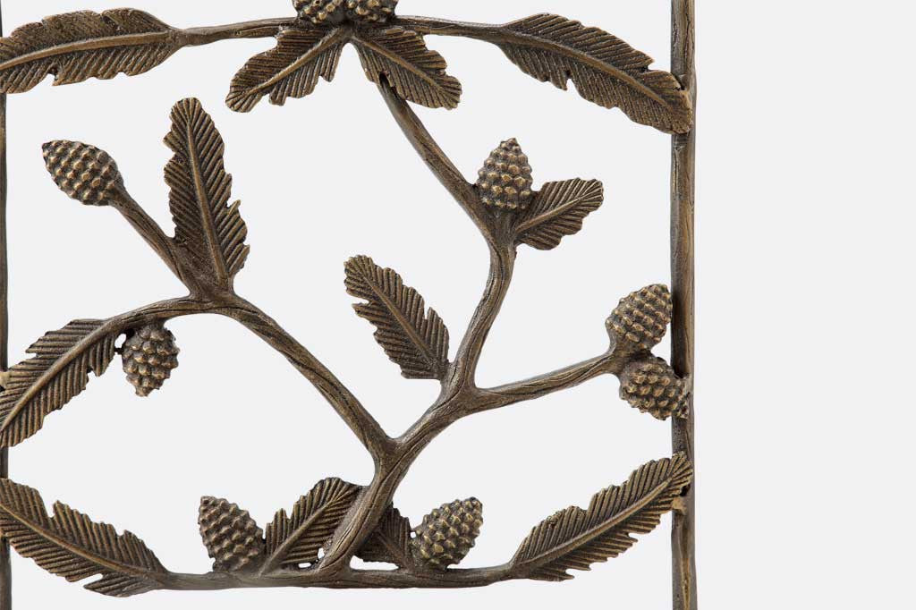 close up of the cast-aluminum details of pinecone and branch